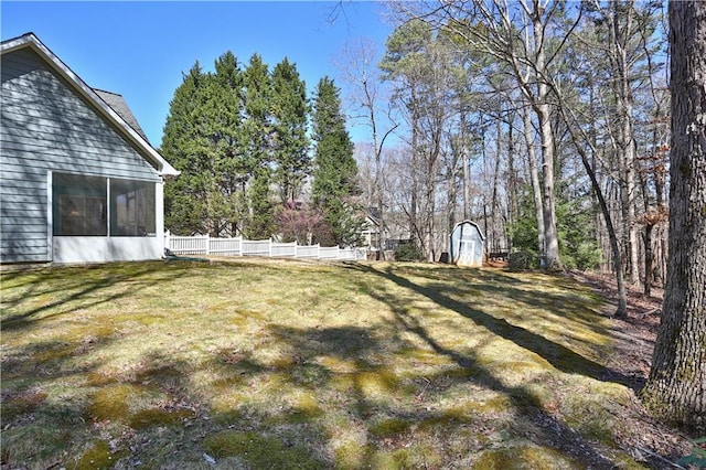 view of yard featuring a storage shed, fence, a sunroom, and an outdoor structure