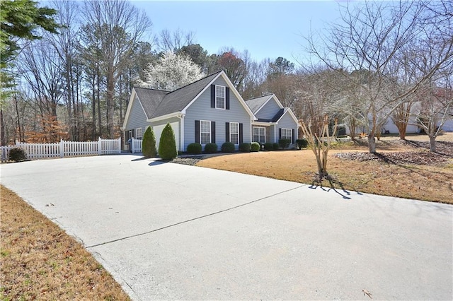 traditional home featuring concrete driveway and fence