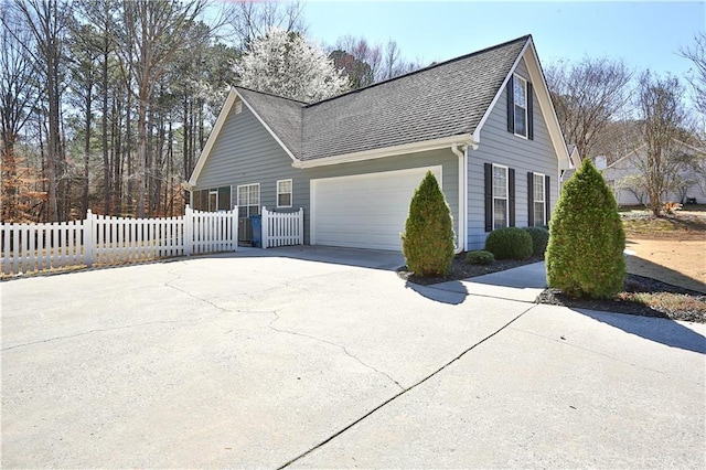 view of home's exterior with a garage, fence, concrete driveway, and roof with shingles