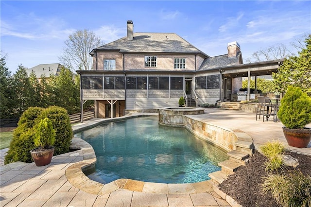 view of swimming pool with a patio, a pool with connected hot tub, outdoor dry bar, and a sunroom