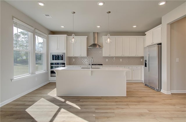 kitchen with white cabinets, stainless steel fridge with ice dispenser, wall chimney exhaust hood, and decorative light fixtures