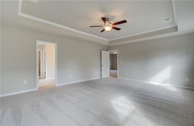 unfurnished room featuring ceiling fan, a raised ceiling, and light carpet