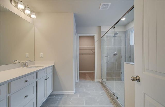 bathroom with tile patterned flooring, vanity, and walk in shower