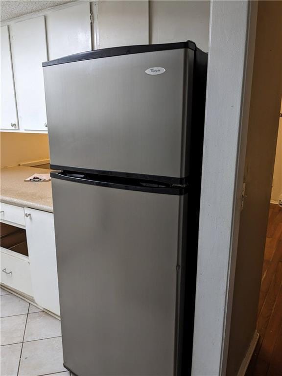 room details featuring light countertops, white cabinets, and freestanding refrigerator