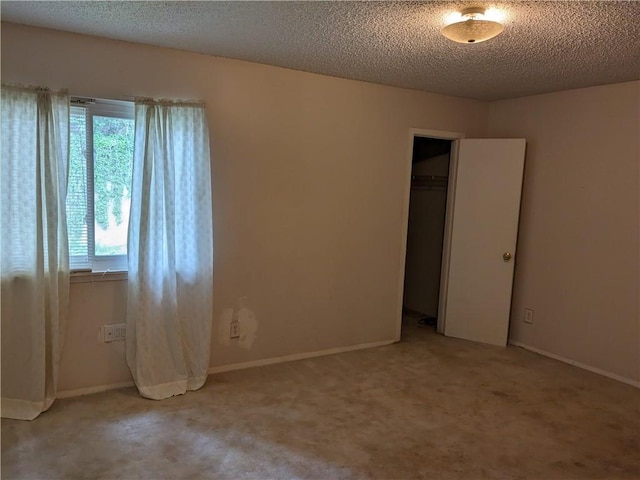 unfurnished room featuring light colored carpet, baseboards, and a textured ceiling