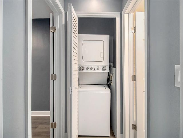 laundry area with stacked washer / drying machine and hardwood / wood-style flooring