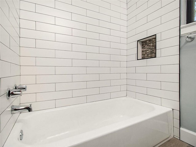 bathroom with hardwood / wood-style floors and tiled shower / bath