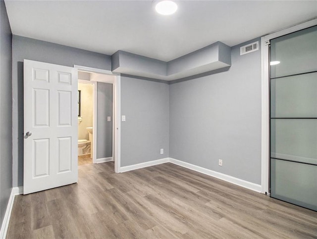 interior space with ensuite bath and light hardwood / wood-style flooring