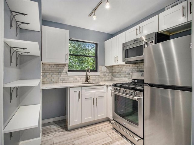 kitchen with appliances with stainless steel finishes, backsplash, light stone counters, sink, and white cabinets