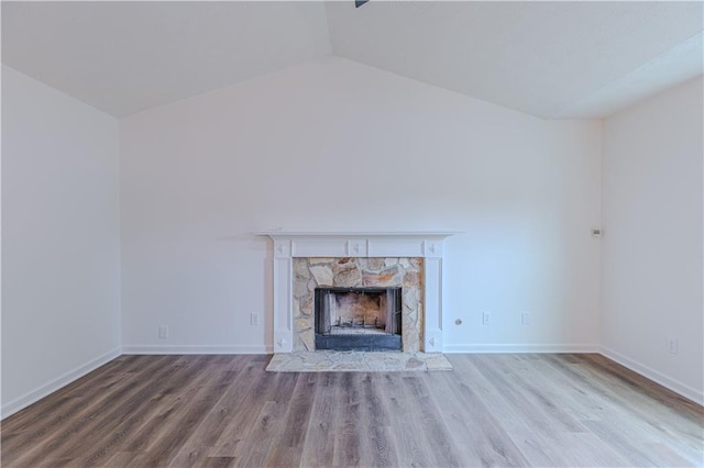 159 Aztec Way SE, Acworth, GA 30102 - unfurnished living room featuring lofted ceiling, wood finished floors, a stone fireplace, and baseboards