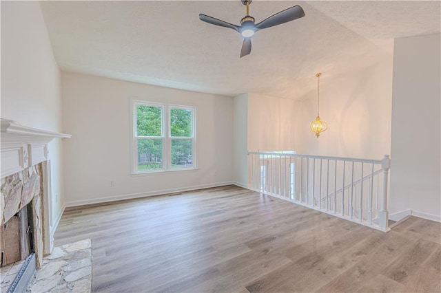 159 Aztec Way SE, Acworth, GA 30102 - unfurnished living room featuring a fireplace, wood finished floors, a ceiling fan, baseboards, and a textured ceiling