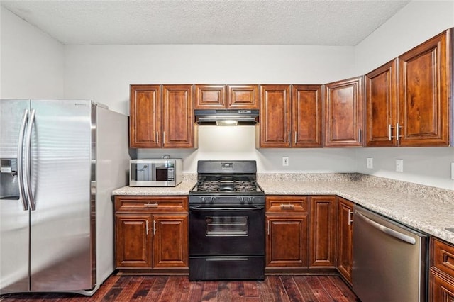 kitchen with stainless steel appliances, under cabinet range hood, dark wood finished floors, light countertops, and a textured ceiling