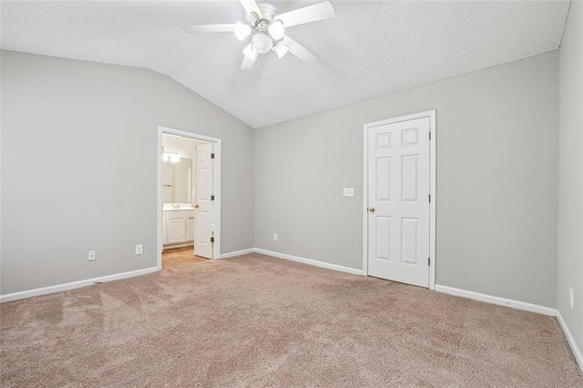 unfurnished bedroom with light carpet, vaulted ceiling, baseboards, ensuite bath, and ceiling fan
