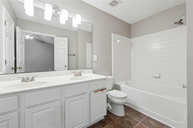 bathroom with toilet, washtub / shower combination, double vanity, and a textured ceiling
