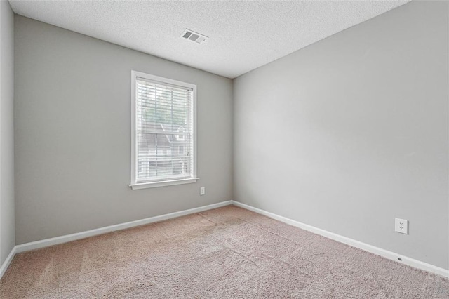 carpeted empty room with a textured ceiling and baseboards