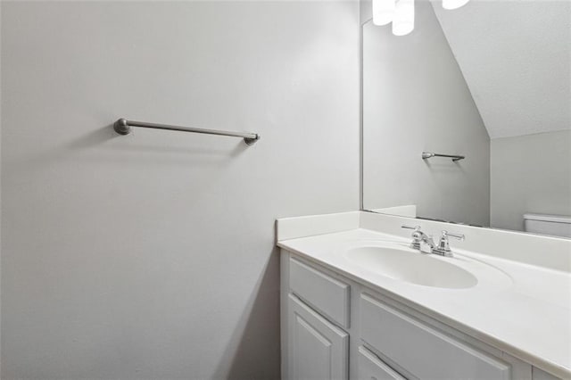 half bathroom with vanity, vaulted ceiling, and toilet