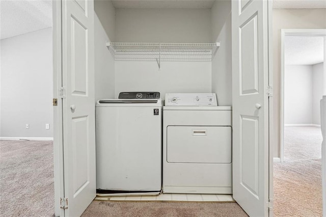 washroom with carpet floors, washing machine and clothes dryer, and baseboards