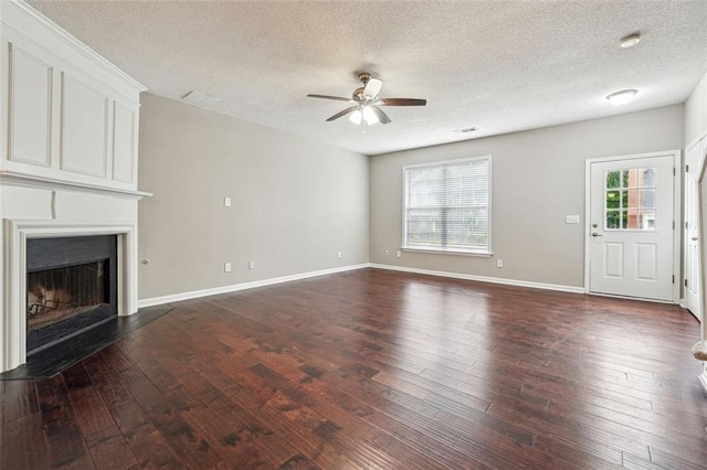 unfurnished living room featuring a ceiling fan, dark wood-style flooring, a textured ceiling, a fireplace, and baseboards