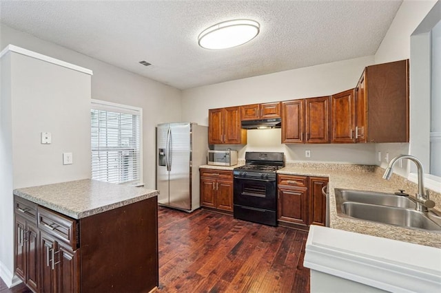 kitchen featuring appliances with stainless steel finishes, a sink, dark wood-style floors, a textured ceiling, and light countertops