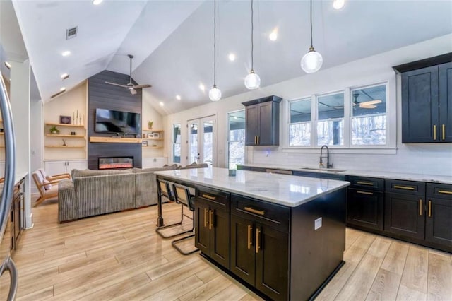 kitchen featuring a large fireplace, ceiling fan, sink, a kitchen island, and hanging light fixtures