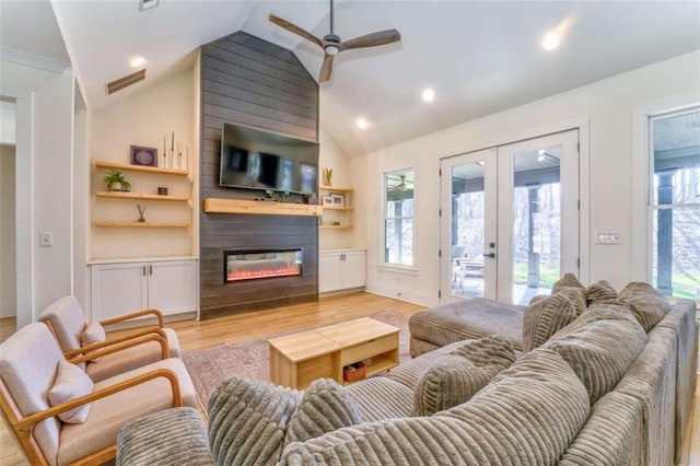 living room with ceiling fan, french doors, vaulted ceiling, a fireplace, and light wood-type flooring