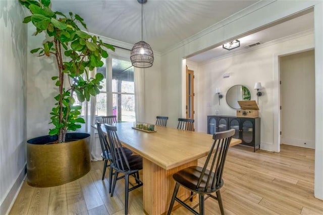 dining area featuring a chandelier, light hardwood / wood-style flooring, and crown molding