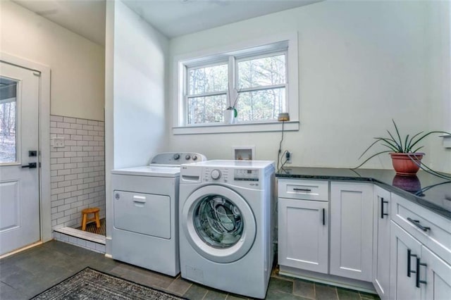 clothes washing area featuring washing machine and clothes dryer, cabinets, and tile walls