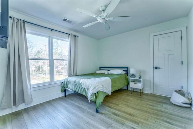 bedroom with multiple windows, ceiling fan, and light wood-type flooring