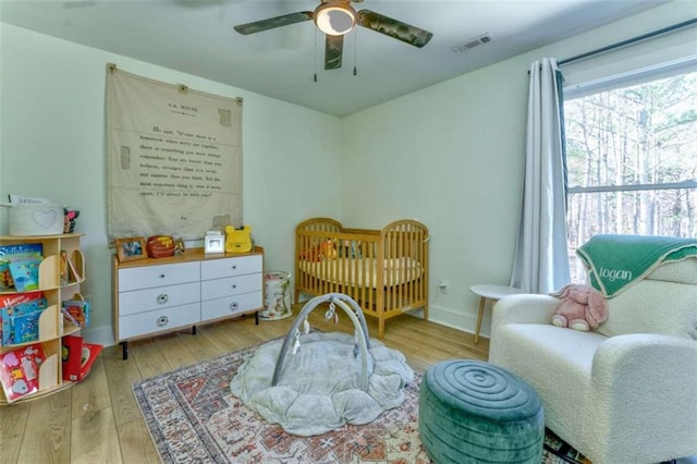 bedroom with ceiling fan, light hardwood / wood-style flooring, and a nursery area