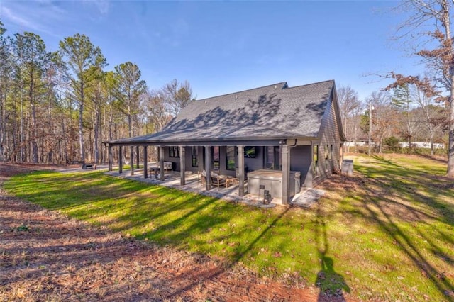 rear view of house featuring a yard, a patio, and a hot tub