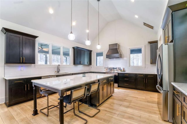 kitchen featuring custom exhaust hood, sink, appliances with stainless steel finishes, tasteful backsplash, and decorative light fixtures