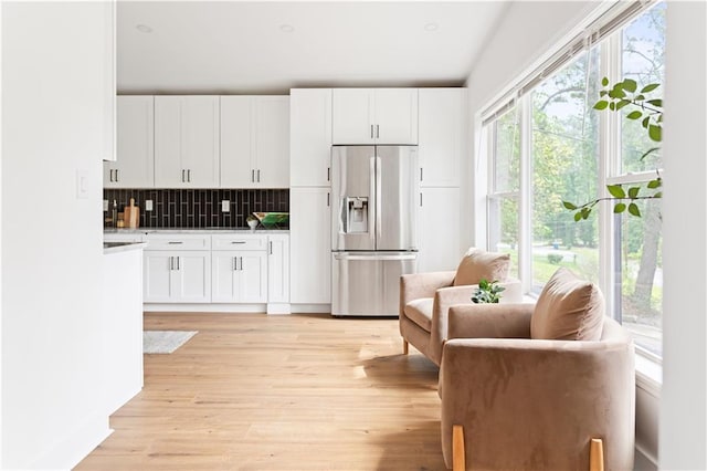 2873 Bob White Dr SW, Atlanta, GA 30311 - kitchen featuring stainless steel fridge with ice dispenser, tasteful backsplash, white cabinetry, light wood-style floors, and light countertops