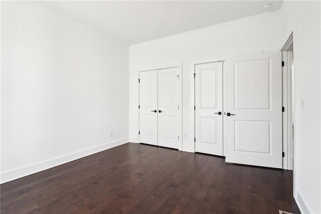 443 Plateau Pl NW, Atlanta, GA 30309 - unfurnished bedroom with baseboards, dark wood-style flooring, and multiple closets