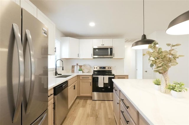 kitchen featuring sink, white cabinetry, stainless steel appliances, light brown cabinetry, and decorative light fixtures