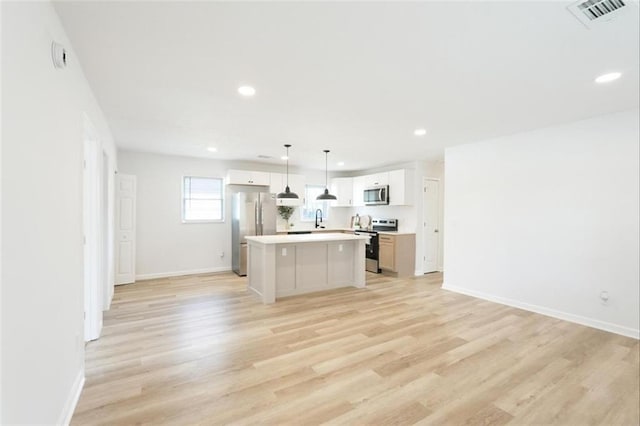 kitchen featuring white cabinetry, a center island, pendant lighting, stainless steel appliances, and light hardwood / wood-style floors