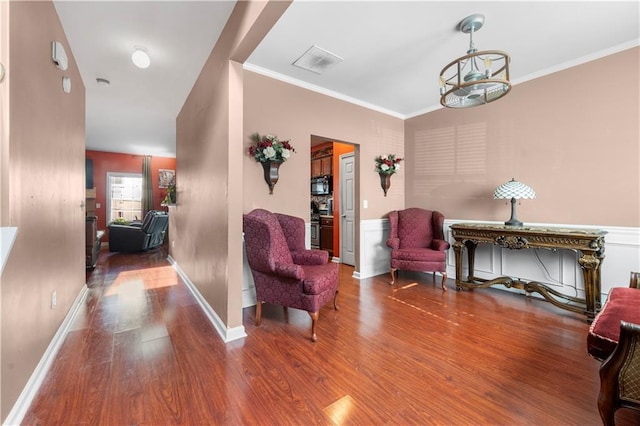 sitting room with hardwood / wood-style floors, a chandelier, and ornamental molding