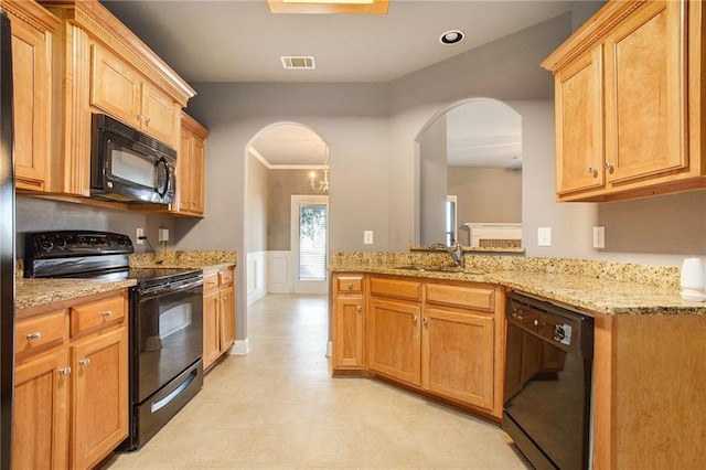 kitchen with black appliances, sink, ornamental molding, light stone counters, and kitchen peninsula