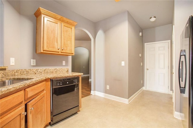 kitchen featuring sink, light stone counters, light brown cabinets, stainless steel fridge, and dishwasher