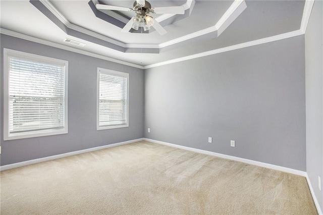 carpeted empty room featuring crown molding, ceiling fan, and a tray ceiling