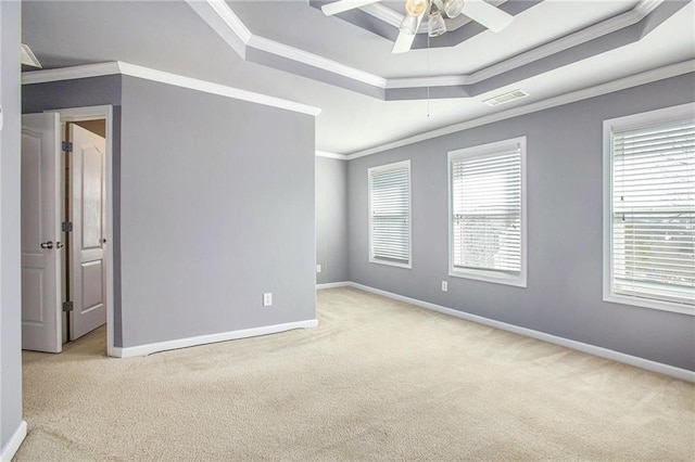 carpeted empty room featuring ornamental molding, ceiling fan, and a tray ceiling