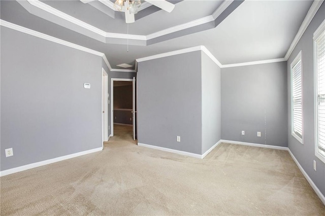 carpeted empty room featuring crown molding, ceiling fan, a tray ceiling, and a healthy amount of sunlight