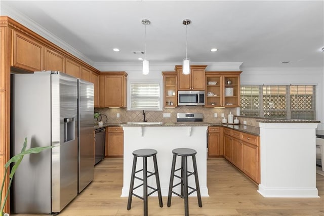 kitchen featuring hanging light fixtures, stainless steel appliances, a kitchen breakfast bar, dark stone countertops, and a kitchen island