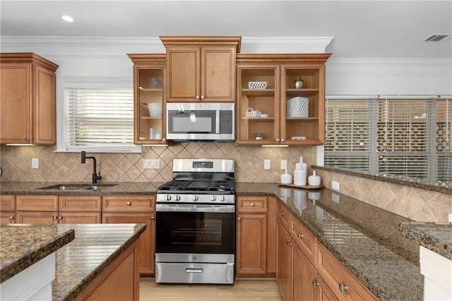 kitchen featuring stainless steel appliances, tasteful backsplash, dark stone countertops, and sink