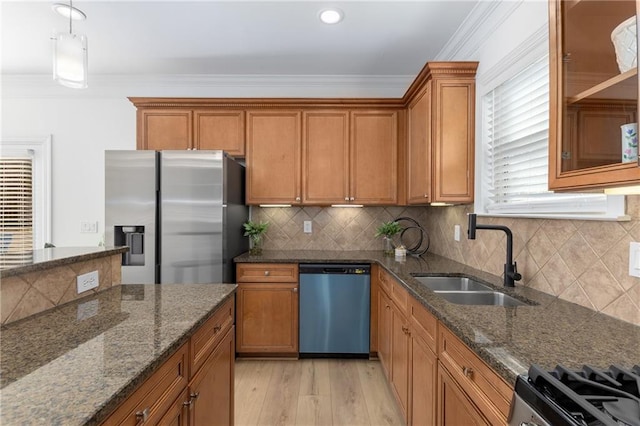 kitchen featuring backsplash, dark stone counters, sink, ornamental molding, and stainless steel appliances