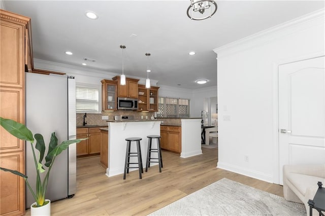 kitchen with pendant lighting, a center island, backsplash, a kitchen bar, and stainless steel appliances