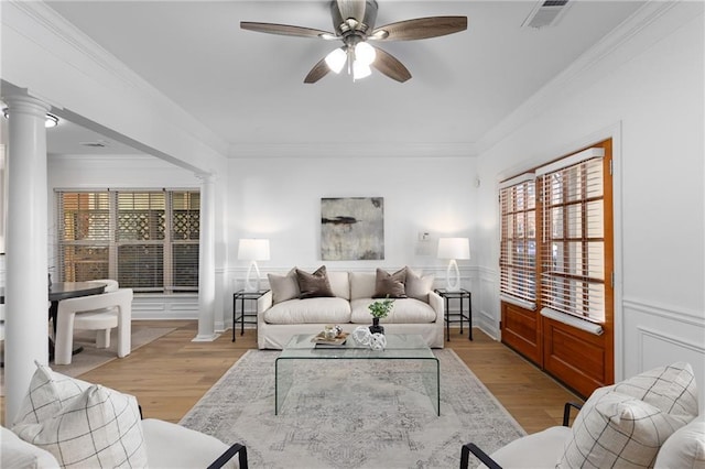 living room featuring decorative columns, crown molding, light hardwood / wood-style flooring, and ceiling fan