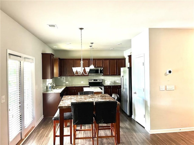 kitchen with dark brown cabinetry, stainless steel appliances, decorative backsplash, and an inviting chandelier