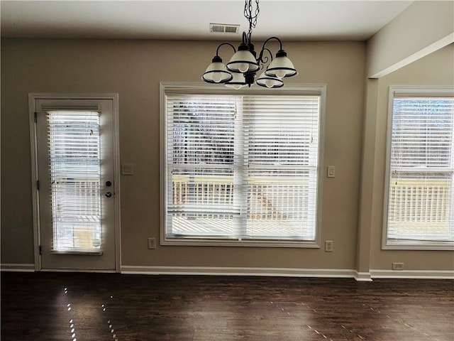 doorway with dark wood-type flooring and an inviting chandelier