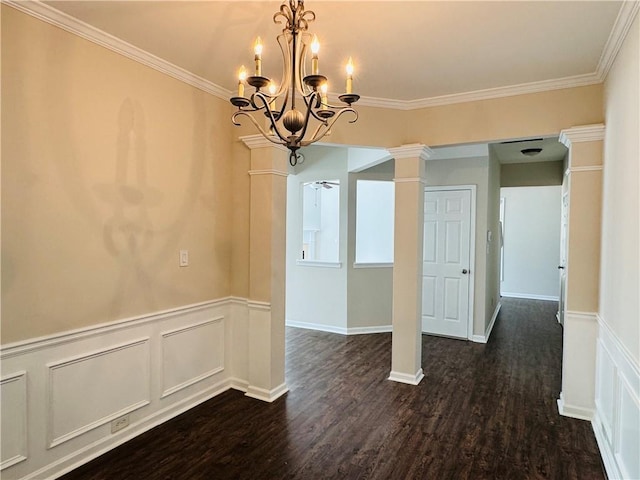 unfurnished room featuring dark hardwood / wood-style floors, ornate columns, ornamental molding, and a chandelier