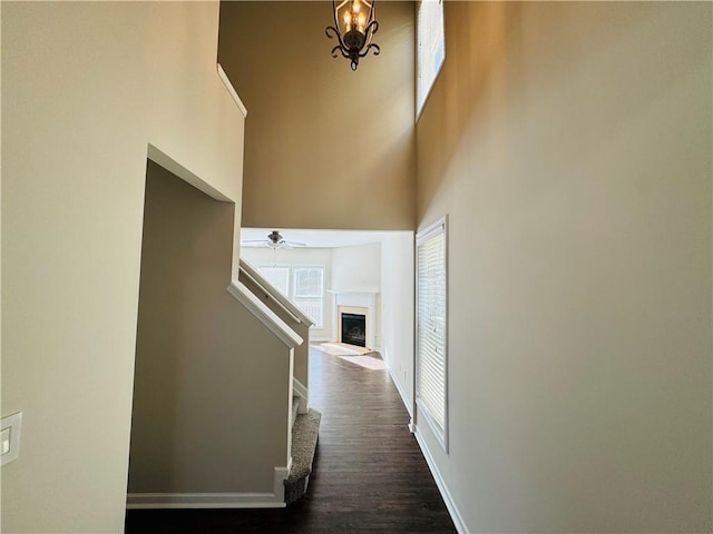 hallway featuring dark hardwood / wood-style floors, a towering ceiling, and an inviting chandelier